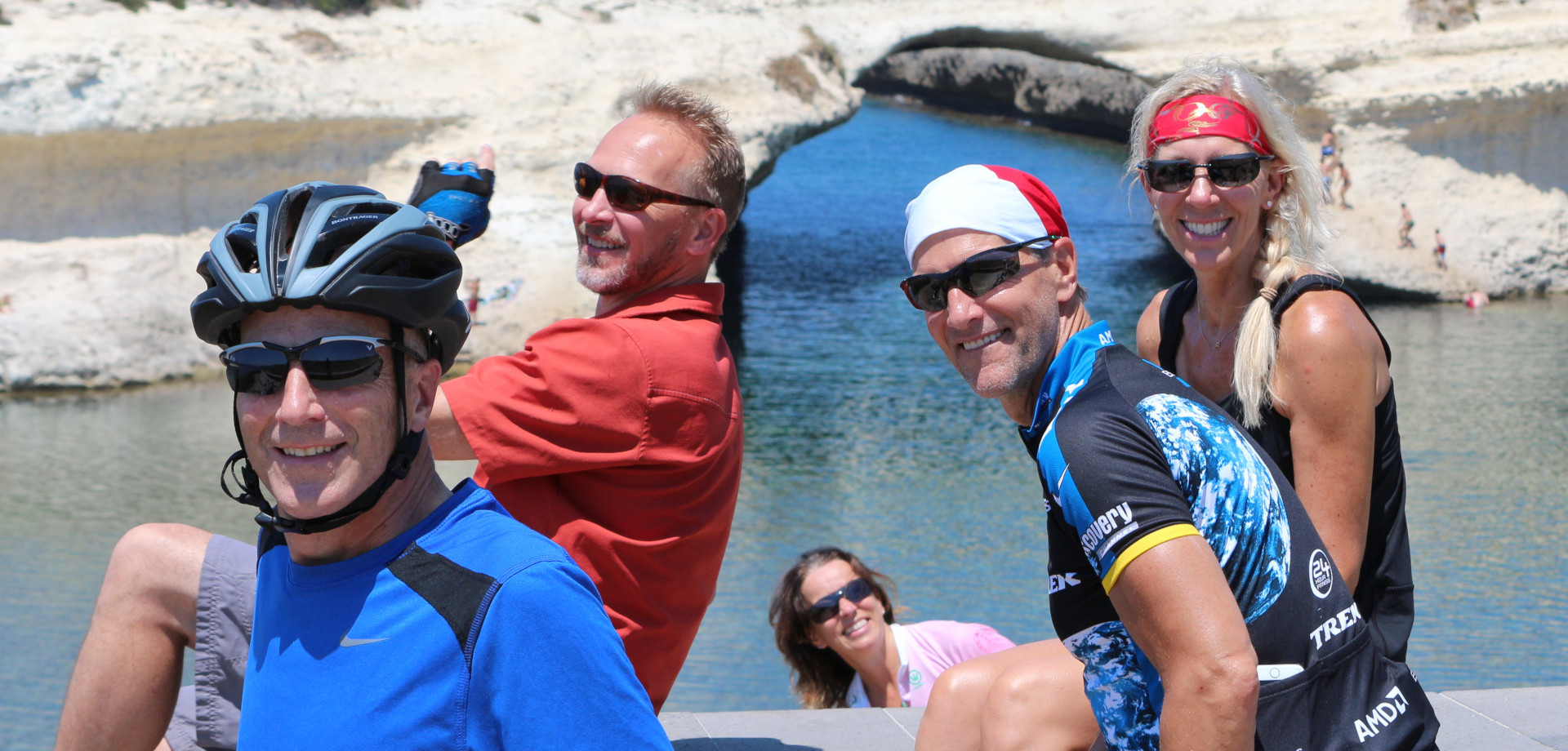 Group of smiling cyclists by the sea in Sardinia