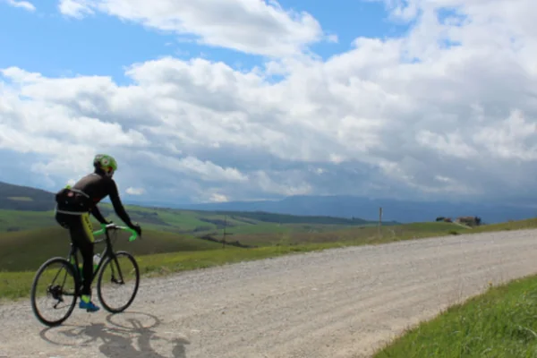 Cyclist riding a white gravel road in Tuscany