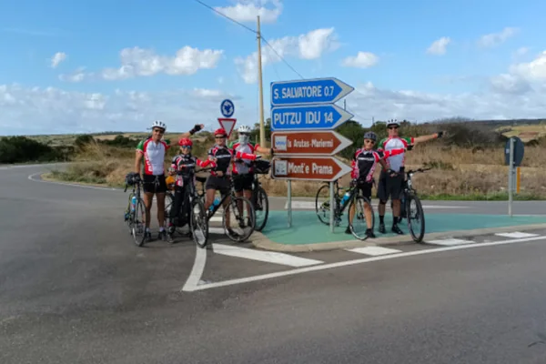 Cyclists ready to ride at a signpost near Putzu Idu, Sardinia